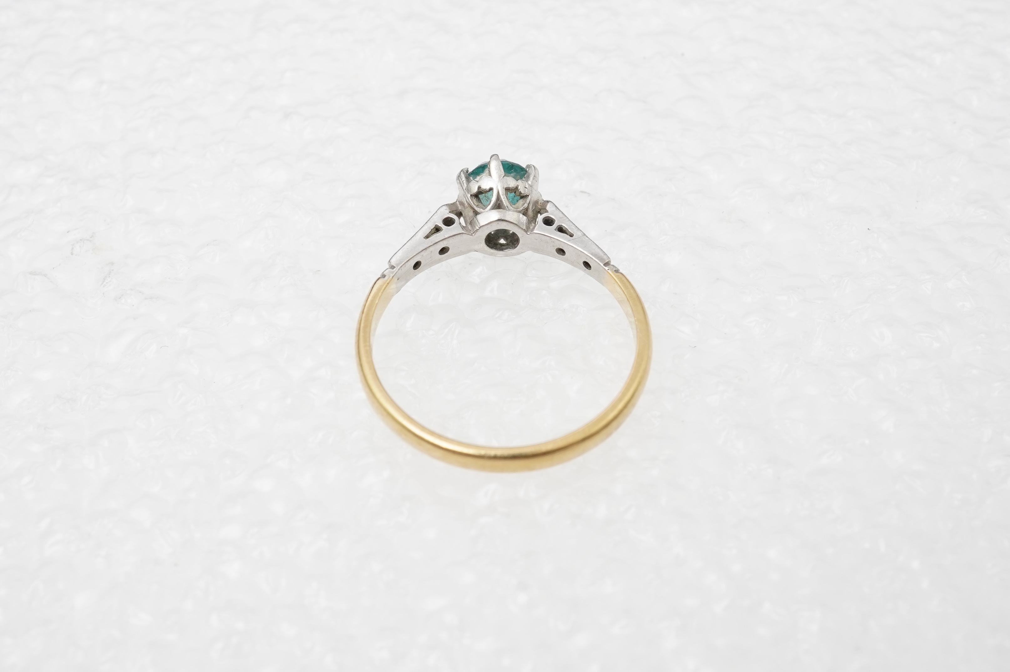 A zircon and diamond ring, mid 20th century, claw-set with a brilliant-cut blue zircon measuring approximately 5mm diameter, to shoulders set with rose-cut diamonds, mounted in gold, size N, stamped 18CT, gross weight ap
